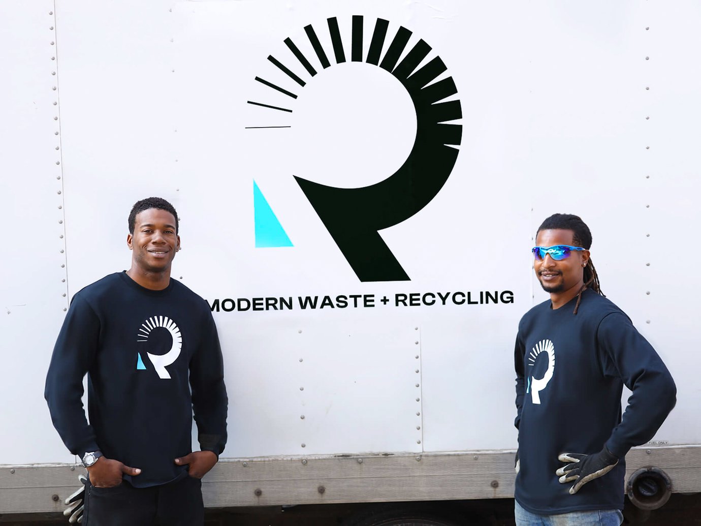 Two drives posing in front of a recycling truck