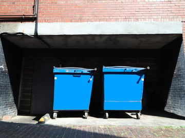 Two front-end dumpsters located behind a office building.